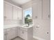 Well-appointed laundry room with sink, white cabinetry, and a window for natural light at 13 Arena Blanca, Ponce Inlet, FL 32127