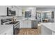 Modern white kitchen with stainless steel appliances, quartz countertops, and a view to the dining area at 2323 Queen Palm Dr, Edgewater, FL 32141