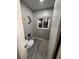 This features a small bathroom with wood-look flooring, a toilet, and a small window at 2404 Victory Palm Dr, Edgewater, FL 32141