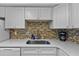 Updated kitchen with white cabinets, quartz countertops, and decorative backsplash at 2625 S Atlantic Ave # 11Nw, Daytona Beach, FL 32118