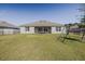 Large backyard with green grass, covered patio with chairs, and privacy fencing, perfect for outdoor activities at 301 Sunset Point Dr, Ormond Beach, FL 32174