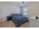 Comfortable carpeted bedroom with a navy and white patterned bed, window with blinds and side table at 301 Sunset Point Dr, Ormond Beach, FL 32174