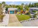 Aerial view of a well-maintained one-story home with a manicured lawn, mature trees, and a long driveway leading to the attached garage at 308 Normandy Ave, New Smyrna Beach, FL 32169