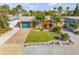 Aerial view of a well-maintained one-story home with a manicured lawn, mature trees, and a long driveway leading to the attached garage at 308 Normandy Ave, New Smyrna Beach, FL 32169