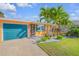 Charming home with a teal garage door, colorful details, and a well-kept lawn with beautiful tropical landscaping at 308 Normandy Ave, New Smyrna Beach, FL 32169