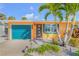 Charming home featuring a lush lawn, rock landscaping, and tall palm trees that offer a bright contrast to the orange-yellow facade at 308 Normandy Ave, New Smyrna Beach, FL 32169