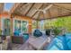 Inviting outdoor patio features a tiki-style gazebo, wood floors, and stylish, bright-blue cushions on comfortable outdoor furniture at 308 Normandy Ave, New Smyrna Beach, FL 32169