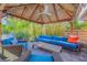 Inviting outdoor patio features a tiki-style gazebo, wood floors, and stylish, bright-blue cushions on comfortable outdoor furniture at 308 Normandy Ave, New Smyrna Beach, FL 32169