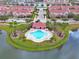 Aerial view of a community pool, featuring palm trees, lounge chairs, and a lakeside setting at 3546 Casalta Cir, New Smyrna Beach, FL 32168