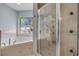 This bathroom has a tiled tub and shower with glass doors, and a stained glass window adds a touch of artistry at 3728 Egret Dunes Dr, Ormond Beach, FL 32176