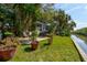 Tranquil waterfront property with lush greenery, featuring a quaint cottage with a screened porch at 4426 Saxon Dr, New Smyrna Beach, FL 32169