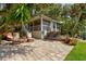Spacious brick patio with a cozy seating area, surrounded by lush landscaping and tropical foliage at 4426 Saxon Dr, New Smyrna Beach, FL 32169