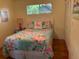 Bright bedroom with large bed, colorful floral bedding, and a sunny window at 4426 Saxon Dr, New Smyrna Beach, FL 32169