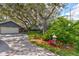Paved driveway leading to a home with mature trees, lush garden and an attached two car garage at 4426 Saxon Dr, New Smyrna Beach, FL 32169