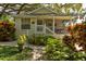 Quaint yellow cottage with a welcoming porch, surrounded by vibrant landscaping and mature trees at 4426 Saxon Dr, New Smyrna Beach, FL 32169