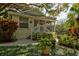 Charming, light yellow home with a cozy front porch surrounded by lush, tropical landscaping and mature trees at 4426 Saxon Dr, New Smyrna Beach, FL 32169