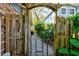 Rustic wooden gate leading to a charming gravel path through lush landscaping at 4426 Saxon Dr, New Smyrna Beach, FL 32169