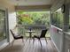 Screened patio with table, two chairs and views of tropical foliage and water at 4426 Saxon Dr, New Smyrna Beach, FL 32169