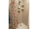 Shower featuring a patterned curtain, tile surround, and toiletry shelves at 4426 Saxon Dr, New Smyrna Beach, FL 32169