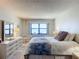Bedroom featuring a well-lit window, dresser, and bedside table with lamps at 4445 S Atlantic Ave # 804, Ponce Inlet, FL 32127