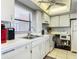 Bright white kitchen featuring white appliances, tiled floor, ample counter space, and a stainless steel sink at 4445 S Atlantic Ave # 804, Ponce Inlet, FL 32127