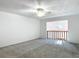 Upstairs bedroom with carpet, ceiling fan, and view to a lower level via a railing at 448 Shorewood Ln, New Smyrna Beach, FL 32168