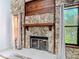 Close up on stone fireplace with dark mantle, tile hearth, and windows on either side at 448 Shorewood Ln, New Smyrna Beach, FL 32168