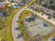 Aerial view showcasing the community tennis courts along with the pool and surrounding neighborhood at 448 Shorewood Ln, New Smyrna Beach, FL 32168