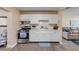 Well-lit kitchen featuring white cabinets, stainless steel gas range and an adjacent living room at 601 N Peninsula Ave, New Smyrna Beach, FL 32169