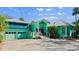 Charming turquoise home with a bright pink front door, lush landscaping, and convenient two-car garage at 61 E Bayshore Dr, Port Orange, FL 32127