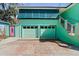 Two-car garage with a bright turquoise exterior and an adjacent staircase leading to the upper level at 61 E Bayshore Dr, Port Orange, FL 32127