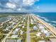 Panoramic aerial view of a beachfront community, capturing homes nestled between the ocean and the intercostal waterway at 6531 Turtlemound Rd, New Smyrna Beach, FL 32169