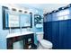 Cozy blue bathroom featuring a dark vanity, sink, toilet, and shelf near the mirror at 6531 Turtlemound Rd, New Smyrna Beach, FL 32169