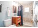 Updated bathroom with a wood vanity, toilet, and tiled walk-in shower with a blue shower curtain at 6531 Turtlemound Rd, New Smyrna Beach, FL 32169