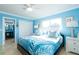 Bedroom with blue accent wall, palm tree bedding, and a large window at 6531 Turtlemound Rd, New Smyrna Beach, FL 32169