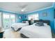 Bright bedroom featuring two queen beds, ceiling fan, and access to a private balcony at 6531 Turtlemound Rd, New Smyrna Beach, FL 32169