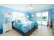 Bedroom with blue accent wall, palm tree bedding and access to outdoor patio at 6531 Turtlemound Rd, New Smyrna Beach, FL 32169