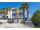 Bright, multi-story home with blue and yellow exterior, accented by surfboards and lush landscaping at 6531 Turtlemound Rd, New Smyrna Beach, FL 32169