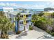 Coastal home featuring palm trees, yellow accents, white railings and a three-car garage near the ocean at 6531 Turtlemound Rd, New Smyrna Beach, FL 32169