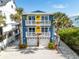 Coastal home featuring palm trees, white railings, surfboards and a three-car garage in a beach community at 6531 Turtlemound Rd, New Smyrna Beach, FL 32169