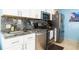 Compact kitchen with stainless steel appliances, sleek white cabinets, and striking granite countertops at 6531 Turtlemound Rd, New Smyrna Beach, FL 32169