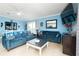 Comfortable living room with blue couches, tile floors, and a large television at 6531 Turtlemound Rd, New Smyrna Beach, FL 32169