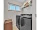 Laundry room with modern washer and dryer units, shelving, and a window for natural light at 662 Wellesley Ct, New Smyrna Beach, FL 32168