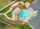 Aerial view of a landscaped backyard featuring a freeform pool, spa, covered lounge areas, and outdoor seating at 701 Kristina Ct, Port Orange, FL 32127