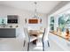 Dining room with round table, white chairs, and decorative wall art, with a modern kitchen in the background at 751 Pine Shores Cir, New Smyrna Beach, FL 32168