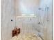 This stunning walk-in shower features light stone tile and a built-in niche with accent lighting at 751 Pine Shores Cir, New Smyrna Beach, FL 32168