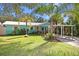 Charming home with lush tropical landscaping, a covered carport, and a light turquoise exterior at 817 E 20Th Ave, New Smyrna Beach, FL 32169