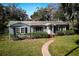 Charming single-story home with a well-manicured lawn, brick walkway, and lush hedges at 820 Faulkner St, New Smyrna Beach, FL 32168