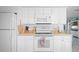 White kitchen with wood countertops and white appliances with adjacent living space at 923 Locust St, New Smyrna Beach, FL 32169
