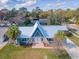 Aerial view of a unique blue home with a white metal roof and well-maintained landscaping at 950 Sand Crest Dr, Port Orange, FL 32127